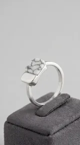 Anillo de plata 925 con diseño geométrico rectangular y detalle de acrílico blanco con vetas negras.
