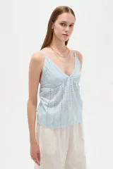 Musculosa blanca de algodón con diseño de broderie, escote en V, tirantes finos regulables y corte holgado.