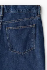 Jean de cinco bolsillos en denim de algodón rígido, con cintura clásica y cierre de botones. Modelo de corte relajado y piernas rectas.