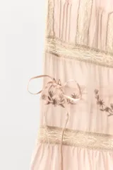 Pantalón de tiro medio confeccionado en viscosa, con cintura elástica ajustable mediante lazada. Presenta detalles de pliegues, bordados florales a tono y aplicaciones de encaje a contraste en la parte inferior, finalizando con un bajo acabado en volantes.