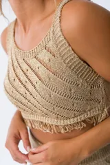 Musculosa tejida color dorado con diseño calado y flecos en el ruedo.