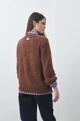 Cardigan de textura suave y efecto fluffy, color beige, con cuello redondo, cierre frontal con botones y puños acanalados.