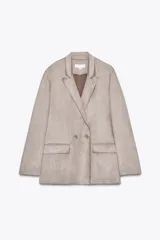 Blazer cruzado de manga larga, color beige claro, con cuello solapa y dos botones frontales. Presenta bolsillos delanteros con solapa.