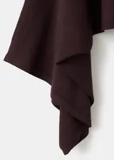 Poncho de punto asimétrico en color bordó, con diseño de capa y cuello barco de mangas amplias.