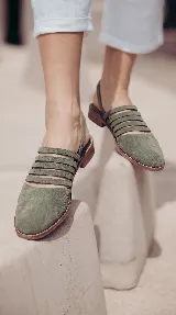 Zueco de cuero color verde militar con diseño de múltiples tiras horizontales en el empeine, puntera cerrada y tira trasera ajustable.