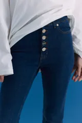 Jean de tiro medio-alto en color azul, con corte oxford y botamanga ancha con tajo frontal. Presenta cierre frontal con cinco botones metálicos visibles.