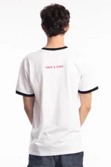 Remera ringer blanca con cuello y bordes de mangas en color negro. Presenta un estampado frontal en color rojo con caracteres estilizados y una estrella central.