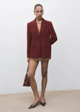 Chaqueta de traje color bordó con solapas de muesca, cierre frontal de un botón, bolsillos con solapa y forro interior.