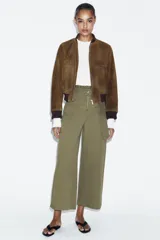 Pantalón de tiro alto con diseño paperbag, pernera ancha y cierre frontal con cremallera. Cuenta con bolsillos laterales de plastrón con solapa y cintura con trabillas.