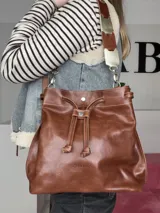 Bolso tipo marinero de cuero genuino negro, con cierre de cordón ajustable, correa corta de cuero y correa larga ajustable de tela.