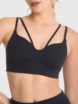 Top deportivo negro con diseño de tiras cruzadas en el frente, escote pronunciado y banda elástica inferior. Cuenta con almohadillas removibles y ofrece soporte medio.