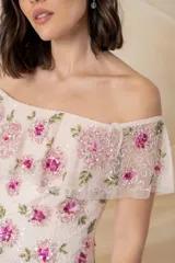 Vestido largo de tul bordado en color rosado, con flores bordadas en tonos fucsia y rosado en la parte superior, tajo lateral y mangas caídas.