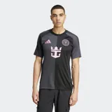 Camiseta de fútbol Adidas alternativa del Inter Miami CF, color negro y gris oscuro con diseño dividido verticalmente. Presenta detalles en rosa, incluyendo el logo de Adidas, el escudo del club y un gráfico central que simula un ancla con corona.