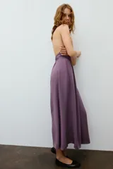 Vestido midi de color morado con cuello halter, tirantes finos ajustables y espalda descubierta. Cuenta con detalles fruncidos en el delantero y la cintura.