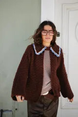 Saco tejido en crochet color marrón, con diseño de textura en relieve, manga larga y cuello grande con bordes en color celeste y crema.