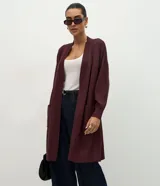 Cardigan alargado Cortelle de punto color bordó, con abertura delantera, mangas largas y bolsillos frontales.