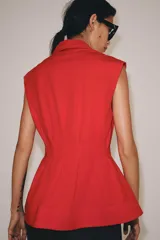 Camisa de cuello solapa y manga sisa, de color blanco. Presenta bajo acabado en peplum y cierre frontal con botones ocultos.