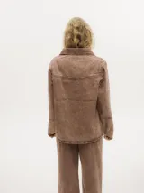 Campera de denim con efecto gastado, cuello camisero, cierre frontal con botones metálicos y corte holgado. Presenta canesú con costuras decorativas en el frente y la espalda, y botones en los puños.