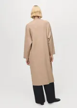 Abrigo largo de tejido de punto en color beige, con diseño recto, cuello solapa y manga larga. Presenta un corte abierto sin cierre frontal.