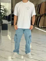 Remera oversize blanca de manga corta, con estampa en la espalda con la inscripción "Concept", un gráfico de pingüino con galera y esferas de líneas.