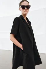 Vestido corto de algodón con cuello solapa, manga corta y cierre frontal con botones. Presenta un diseño evasé con bolsillos laterales ocultos en las costuras.