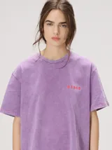 Remera oversize de corte cuadrado, color lila con efecto acid wash, cuello redondo y pequeño gráfico frontal en color rojo.