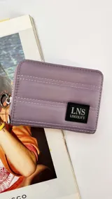 Billetera corta de diseño acolchado, color lila, con cierre perimetral y parche con logo de la marca Lincoln's en el frente. Incluye compartimentos internos para tarjetas y billetes.