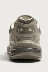 Zapatilla deportiva tipo running color marrón, con parte superior confeccionada en combinación de piezas de malla, gamuza y material sintético. Posee suela con volumen y diseño irregular.