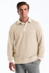 Sweater de tejido tipo waffle en color beige, con cuello polo, cierre frontal parcial con botones y mangas largas con puños elásticos.