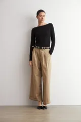 Pantalón pinzado beige de corte ancho y relajado, tiro alto, con bolsillos laterales y detalle de doblez en los bajos.