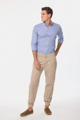 Pantalón de vestir color verde oliva, de corte recto, con bolsillos laterales y traseros. Se ajusta a la cintura con cinturón de cuero marrón.