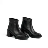 Bota corta de cuero negro con plataforma y taco cuadrado. Presenta un diseño de textura acanalada en la parte posterior del talón y cierre lateral.