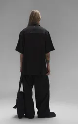 Camisa de manga corta con calce oversize, confeccionada en tejido de lyocell, con cuello clásico y cierre frontal de botones.