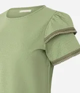Blusa de manga corta color verde, con cuello redondo y detalles de terminación en efecto ganchillo en las mangas. Confeccionada en tejido de algodón con textura sutil.