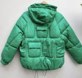 Campera puffer verde con capucha, cierre frontal con cremallera y bolsillos con solapa.