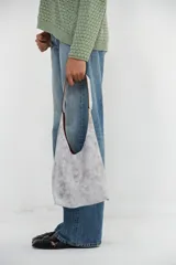 Mini cartera tipo tote de cuero con acabado craquelado en tono blanco y grisáceo. Presenta un diseño de hombro con asa ancha integrada, cierre magnético y bolsillo interior.