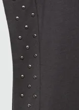 Camiseta blanca de algodón con cuello redondo y mangas cortas con tachas decorativas en los hombros.