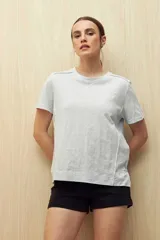 Remera de manga corta color blanco con cuello redondo y costuras verticales decorativas en el frente.