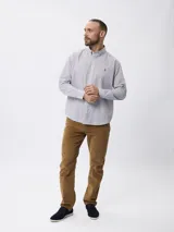 Camisa de manga larga con estampado de microcuadros en tonos azul y blanco. Presenta cuello clásico con botones, cierre frontal abotonado y detalle de logo bordado en el pecho.