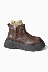 Botas de cuero sintético color marrón con suela de plataforma gruesa color negro y detalle de media de punto acanalado en color beige integrada en la caña.