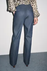 Pantalón de tiro alto confeccionado en algodón, con corte recto y diseño minimalista. Presenta bolsillos laterales, raya planchada en el delantero y cierre frontal con cremallera, botón y ganchos metálicos.