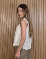 Musculosa de lino color blanco, de corte holgado, con cuello en V, detalles de tablas y frunces en los hombros, y dobladillo desflecado.