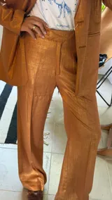 Pantalón sastrero de corte recto y tiro medio, confeccionado en tejido de lino con destellos de lurex, con cierre frontal y trabillas para cinturón.