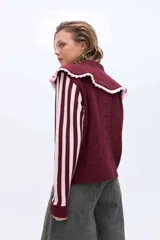 Buzo de punto color rosado con mangas largas a rayas marrones y rosadas. Presenta un doble cuello XL en color rosado con borde marrón y terminación de rulo, además de un cuerpo con detalles de calados y puntos tejidos.