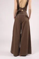 Pantalón marrón de corte palazzo, tiro alto, con pliegues frontales y pespuntes blancos decorativos.