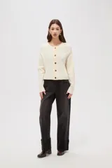 Cardigan de tejido acrílico con textura acanalada, corte ajustado al cuerpo, cuello redondo y cierre frontal con botones metálicos.