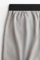 Short deportivo de tejido funcional con tecnología DryMove para absorción de sudor. Presenta cintura elástica con cordón oculto, bolsillos laterales al bies, aberturas en el bajo y detalles reflectantes.