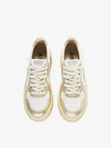 Zapatillas de plataforma Autry Medalist, con diseño inspirado en el tenis de los años 80. Presentan una combinación de cuero blanco y cuero laminado color platino, con microperforaciones en la puntera para mayor transpirabilidad y suela de plataforma alta en tono crema.