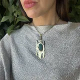 Collar dorado con cadena de eslabones gruesos y colgante de bronce rústico con una piedra ovalada color verde esmeralda.