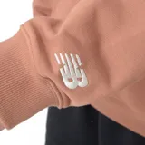 Buzo color beige con cierre de media cremallera, cuello alto y bolsillo tipo canguro. Estampado frontal con el logo de New Balance y la leyenda "Athletic Dept.".